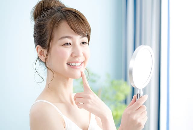 鏡で歯を見る女性
