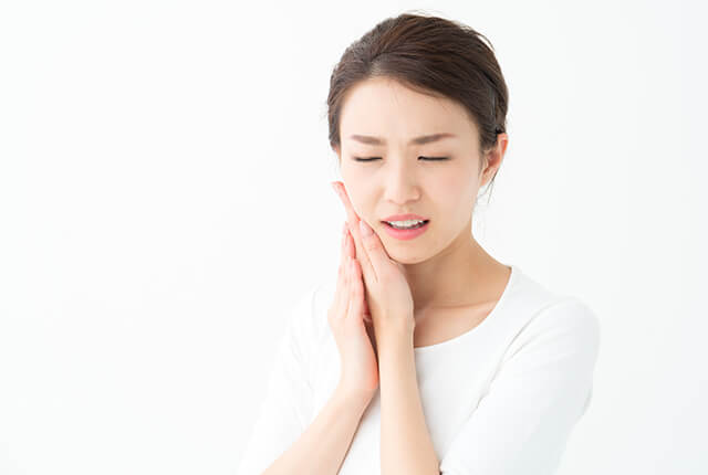 痛そうに右ほほをおさえる女性